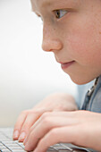 Extreme close up of a boy typing on laptop computer keyboard