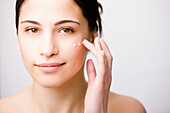 Close up of a young woman applying moisturizer on her cheek