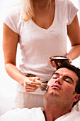 Woman applying shaving cream on man face