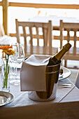 Unopened champagne bottle in an ice bucket on a restaurant table