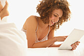 Woman Lying on Bed Using Digital Tablet