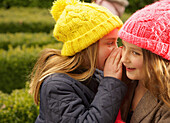 Young Girl Whispering in Friends Ear