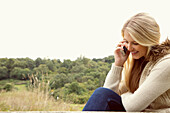 Young Woman in Field Using Smartphone