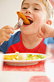 Young Boy Eating Fish fingers and Vegetables