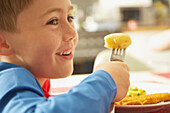 Young Boy Eating Fish fingers and Vegetables