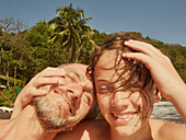 Portrait happy father and son laughing and hugging on sunny beach, Saint Vincent and the Grenadines