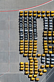 View from above empty yellow and black luggage carts on sunny airport tarmac