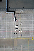 View from above passenger boarding bridge and service vehicles on sunny airport tarmac