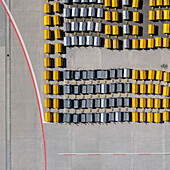 View from above empty yellow and black luggage carts in rows on sunny airport tarmac