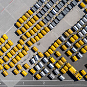 View from above empty yellow and black luggage carts on sunny airport tarmac