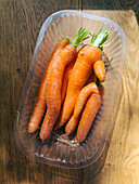 Still life view from above rustic carrots in plastic container