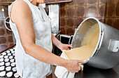 Dough is filled into a piping bag in a bakery kitchen
