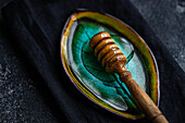 Top view of organic honey dripping from dipper on leaf plate