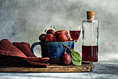 Fresh organic plums and homemade plum liqueur on a rustic table