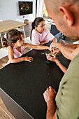 Father and daughters bake together in a modern kitchen