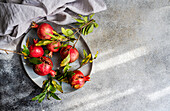 Top view of fresh pomegranates with leaves on a plate