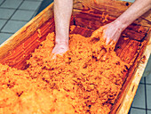 Hands mixing traditional Sobrasada in a wooden trough