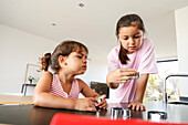 Two young girls baking biscuits in a modern kitchen