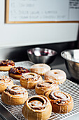Fresh vegan cinnamon buns with white and red fruit glaze on a chilled shelf