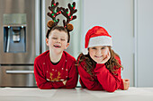 Twins in Christmas costumes in a festive kitchen