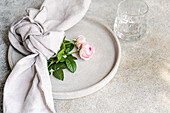 Styled table setting with rosebuds and concrete plate