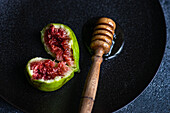 Organic honey drizzled over fig on black plate, top view