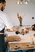 Private chef serving wine to friends at a rustic table