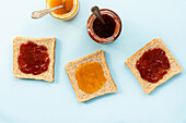 Toast spread with strawberry and peach jam on a table