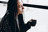 Stylish Caucasian woman with pigtails enjoying coffee in a café