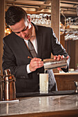 Professional bartender pours a cocktail into a glass at work