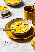 Creamy pumpkin soup with feta and seeds on rustic pottery