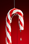 Sauce on a candy cane against a red background