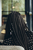 Elegant woman with braided hair seen from behind in a café