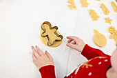Kind beim Backen von Weihnachtsplätzchen in festlichen Pullovern