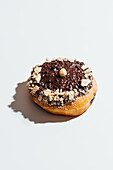 Vegan cream donut with chocolate icing and nut toppings