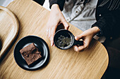 Woman enjoying coffee and a brownie at a wooden table