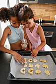 Children decorating biscuits together in a modern kitchen