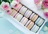 Colourful macaroons in a gift box and roses