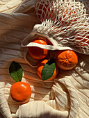 Top view of mandarins in a mesh bag on a textured fabric