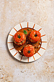 Top view of roasted stuffed tomatoes with brown rice on ceramic plate