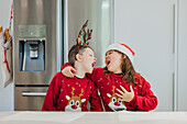 Fröhliche Zwillinge in Weihnachtspullis, die zusammen lachen