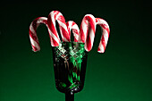 Christmas candy canes in a green glass vase on a dark background