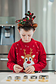 Festively dressed child decorating Christmas biscuits