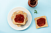 Mit Erdbeermarmelade belegter Toast auf einem Teller