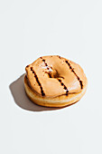 Donut with coffee glaze and espresso drizzle against a light background