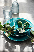 Table setting with feijoas and turquoise dishes in sunlight