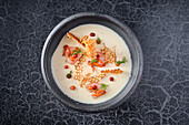 Top view of gourmet cream soup with shrimp and garnish