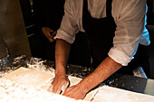 Cooks preparing dough in a busy restaurant kitchen