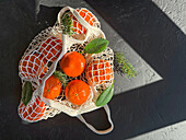Top view of mandarins in a mesh bag on a textured surface