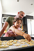 Father and daughter baking biscuits together in the kitchen